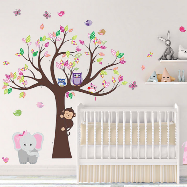 Children's room with a tree wall decal, crib, and various animal stickers.